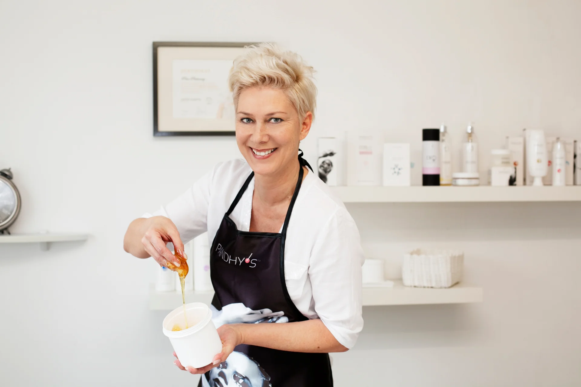 Petra Pischounig gießt lächelnd Sugaring-Paste in einen Becher