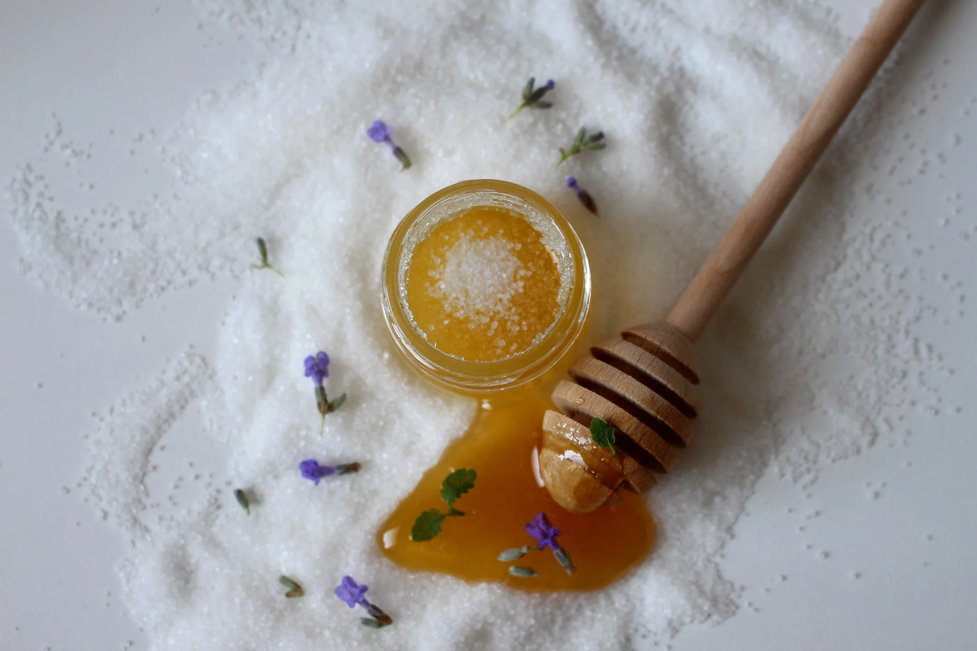 Glas mit Zuckerpaste und Honiglöffel auf Zucker und Lavendel